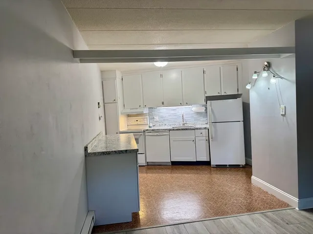 a kitchen with stainless steel appliances a refrigerator and white cabinets