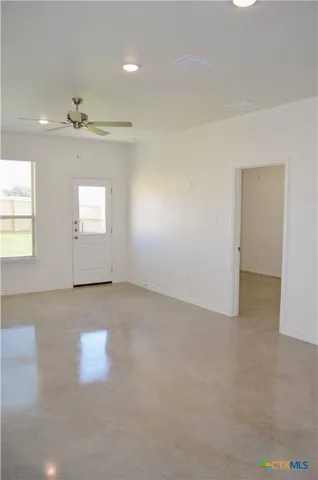 an empty room with a chandelier fan and windows