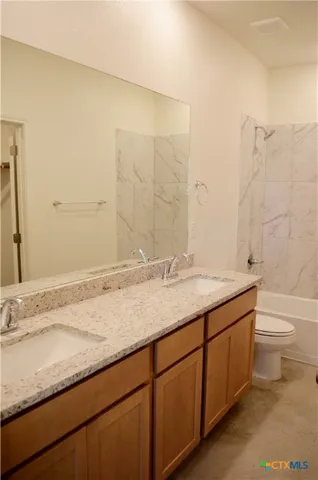 a bathroom with a granite countertop sink a toilet and a mirror