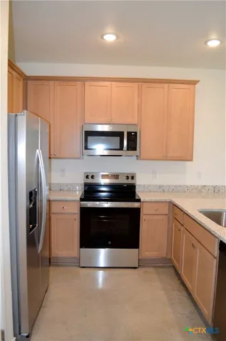 a kitchen with stainless steel appliances granite countertop a refrigerator stove and sink