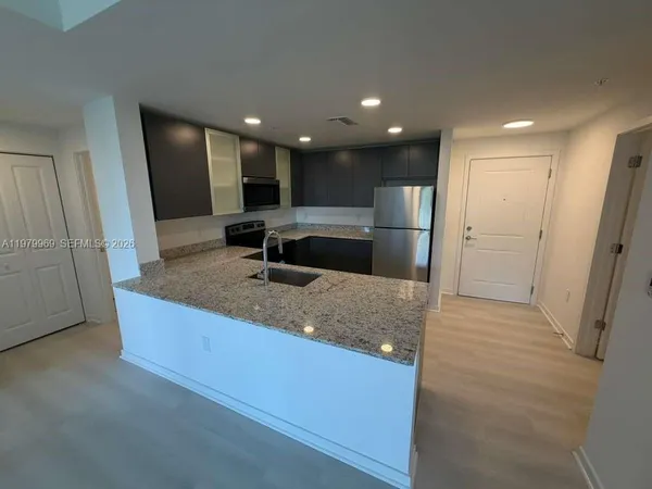 a kitchen with stainless steel appliances granite countertop a sink and a refrigerator