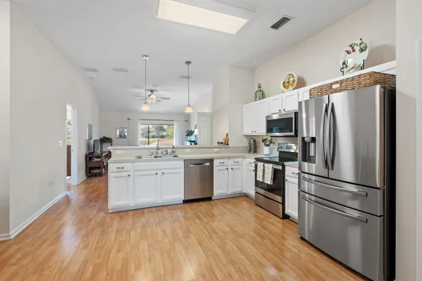 a kitchen with stainless steel appliances granite countertop a stove a sink dishwasher and a refrigerator with wooden floor