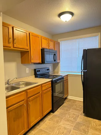a kitchen with stainless steel appliances granite countertop a refrigerator a stove and a sink