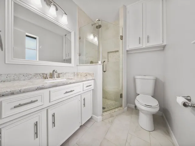 a bathroom with a granite countertop toilet sink and mirror