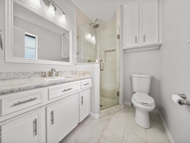 a bathroom with a granite countertop toilet sink and mirror