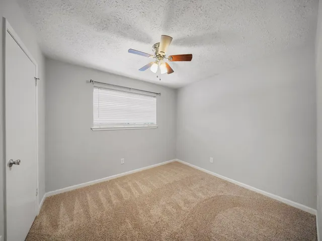an empty room with a window and a fan