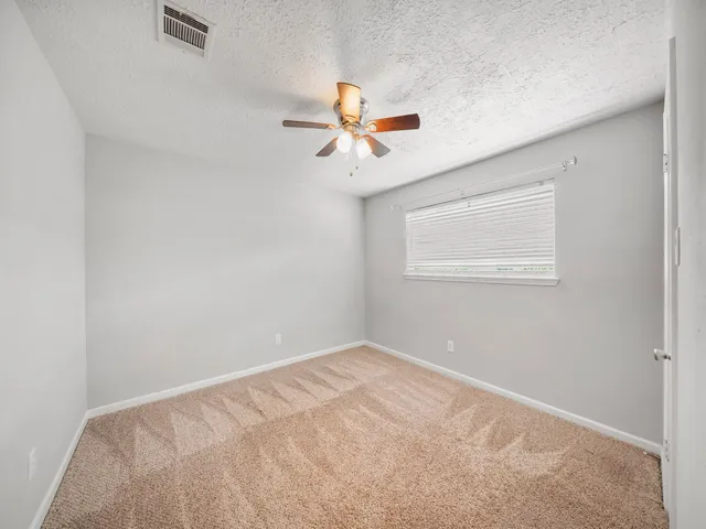an empty room with windows and fan