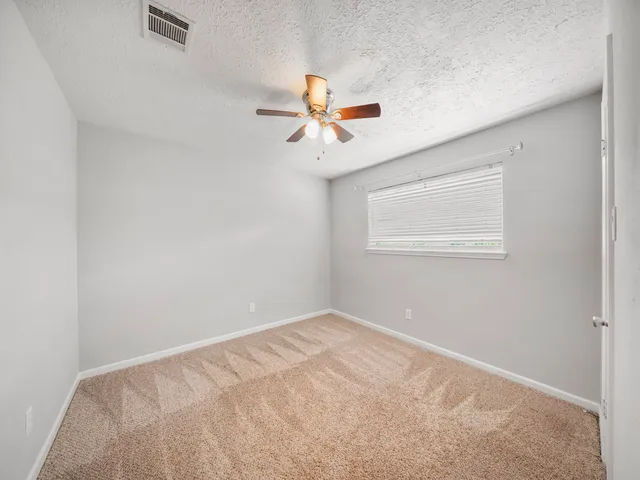 an empty room with windows and fan