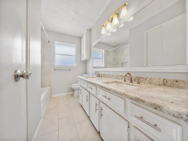 a bathroom with a granite countertop sink a toilet a mirror and vanity