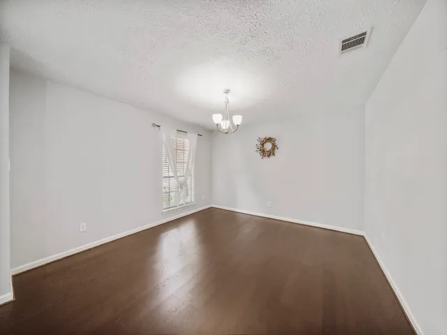 an empty room with wooden floor chandelier fan and windows