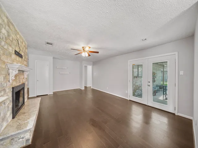 a view of an empty room with wooden floor and a fireplace