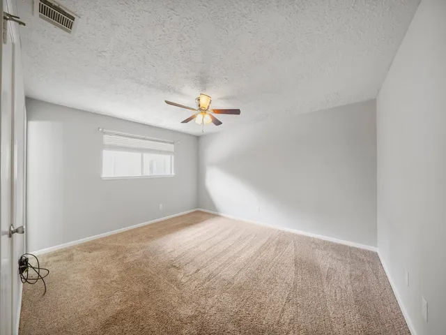 an empty room with windows and fan