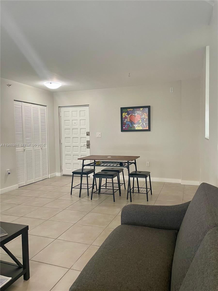 700 Northeast 63rd Street, Unit D203 Miami, FL 33138 - Photo 4 of 36 a living room with furniture and a dining table with floor to ceiling window