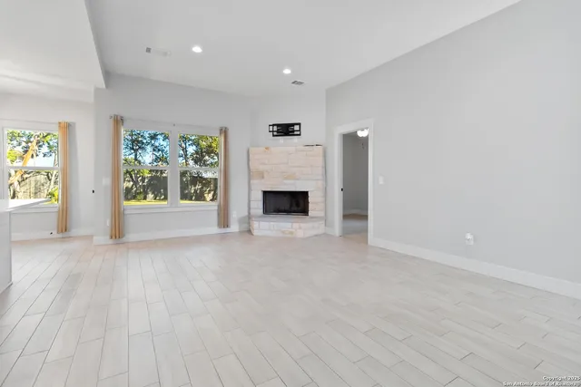 an empty room with windows and fireplace