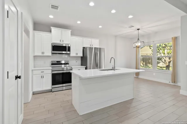 a kitchen with kitchen island white cabinets and stainless steel appliances
