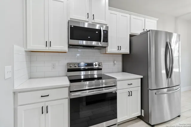 a kitchen with stainless steel appliances white cabinets white stove a microwave and a refrigerator