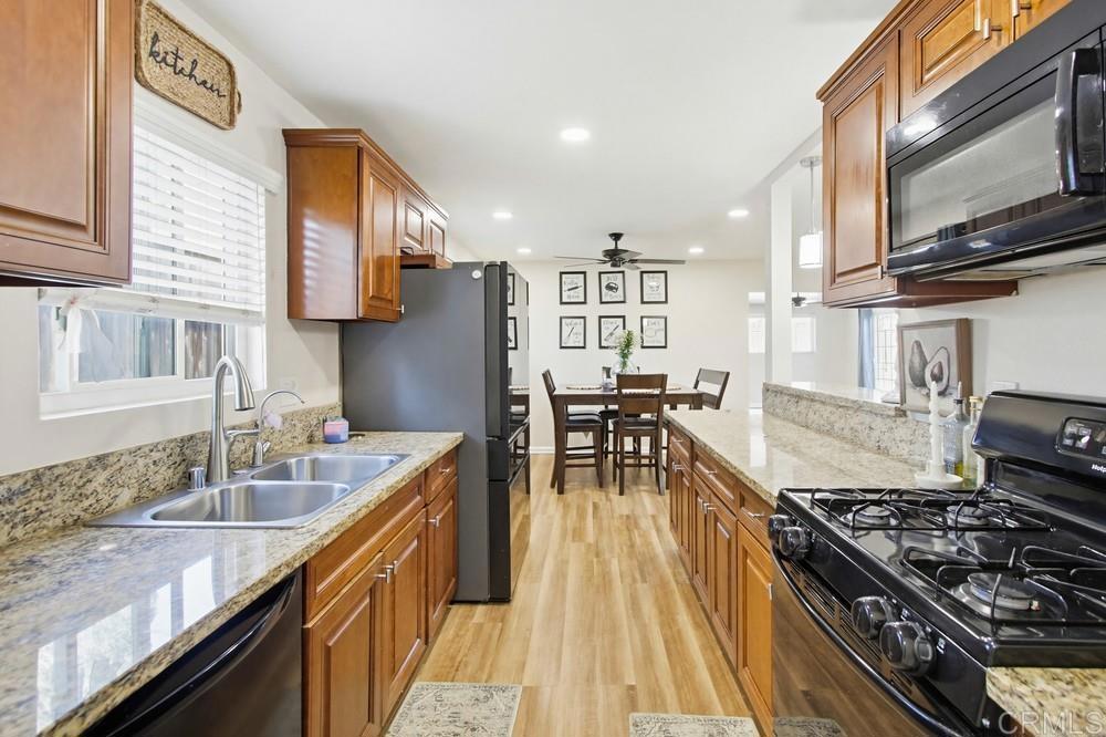 8838 Innsdale Avenue Spring Valley, CA 91977 - Photo 14 of 38 a kitchen with stainless steel appliances granite countertop a stove top oven a sink a dining table and chairs with wooden floor