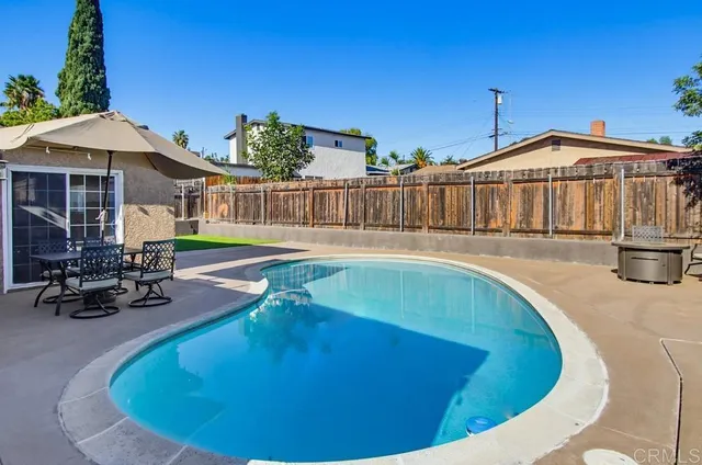 a view of a swimming pool with a lounge chairs and wooden fence