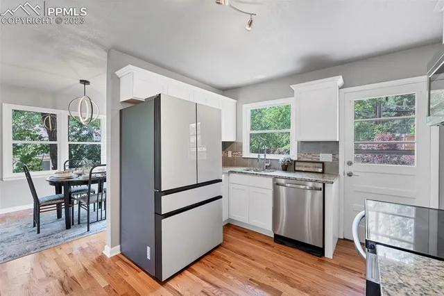 a kitchen with stainless steel appliances granite countertop a refrigerator a stove a sink and a dining table with wooden floor