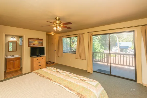 a spacious bedroom with a large bed and a chandelier fan