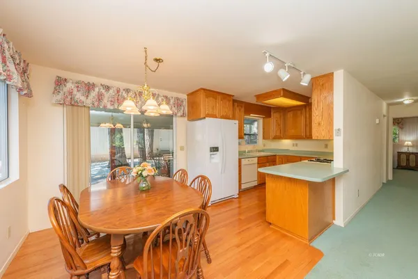 a kitchen with stainless steel appliances kitchen island granite countertop a table chairs and a refrigerator