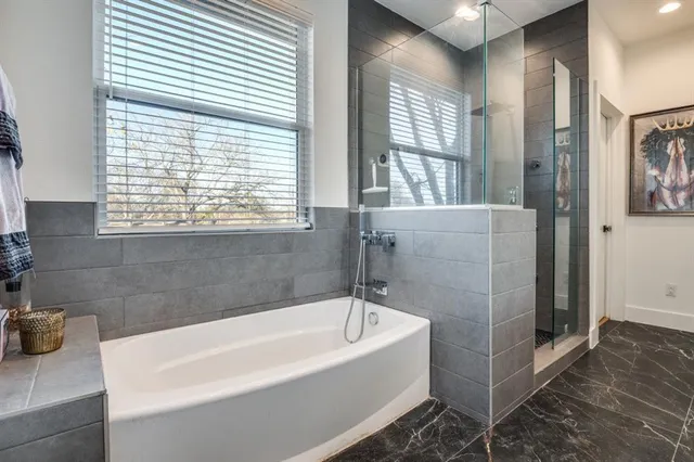 a white bath tub sitting in a bathroom next to a window
