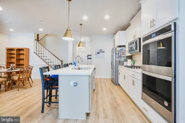 a kitchen with a sink a microwave a stove and chairs