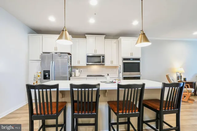 a kitchen with stainless steel appliances a dining table chairs refrigerator and microwave