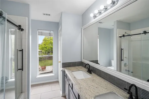 a bathroom with a granite countertop sink a mirror and a shower