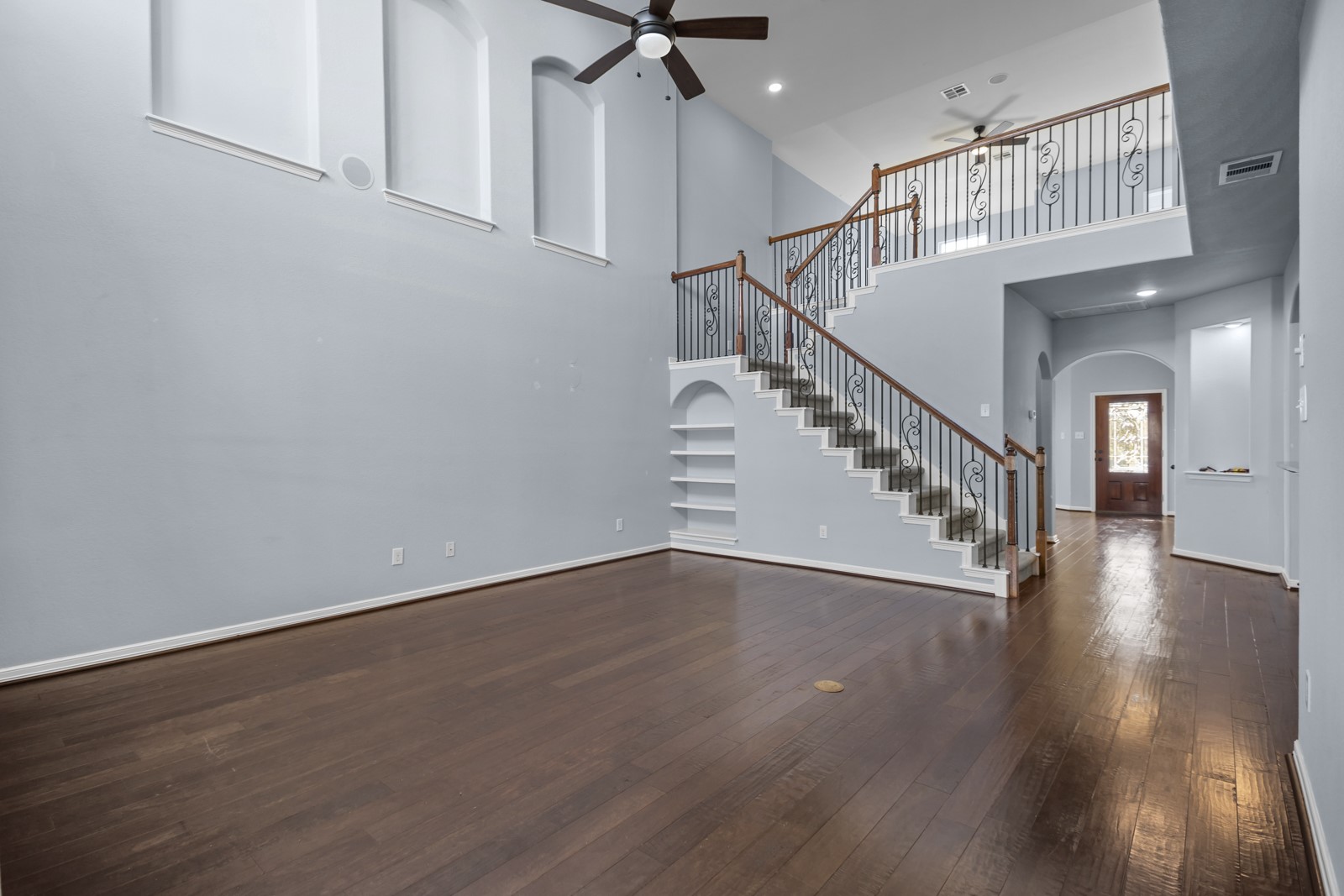 245 Razzmatazz Trail Buda, TX 78610 - Photo 16 of 40 Unfurnished living room with arched walkways, ceiling fan, dark wood finished floors, a high ceiling, and recessed lighting
