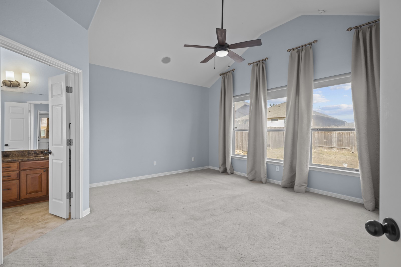 245 Razzmatazz Trail Buda, TX 78610 - Photo 18 of 40 Unfurnished bedroom with light colored carpet, lofted ceiling, ensuite bathroom, and ceiling fan