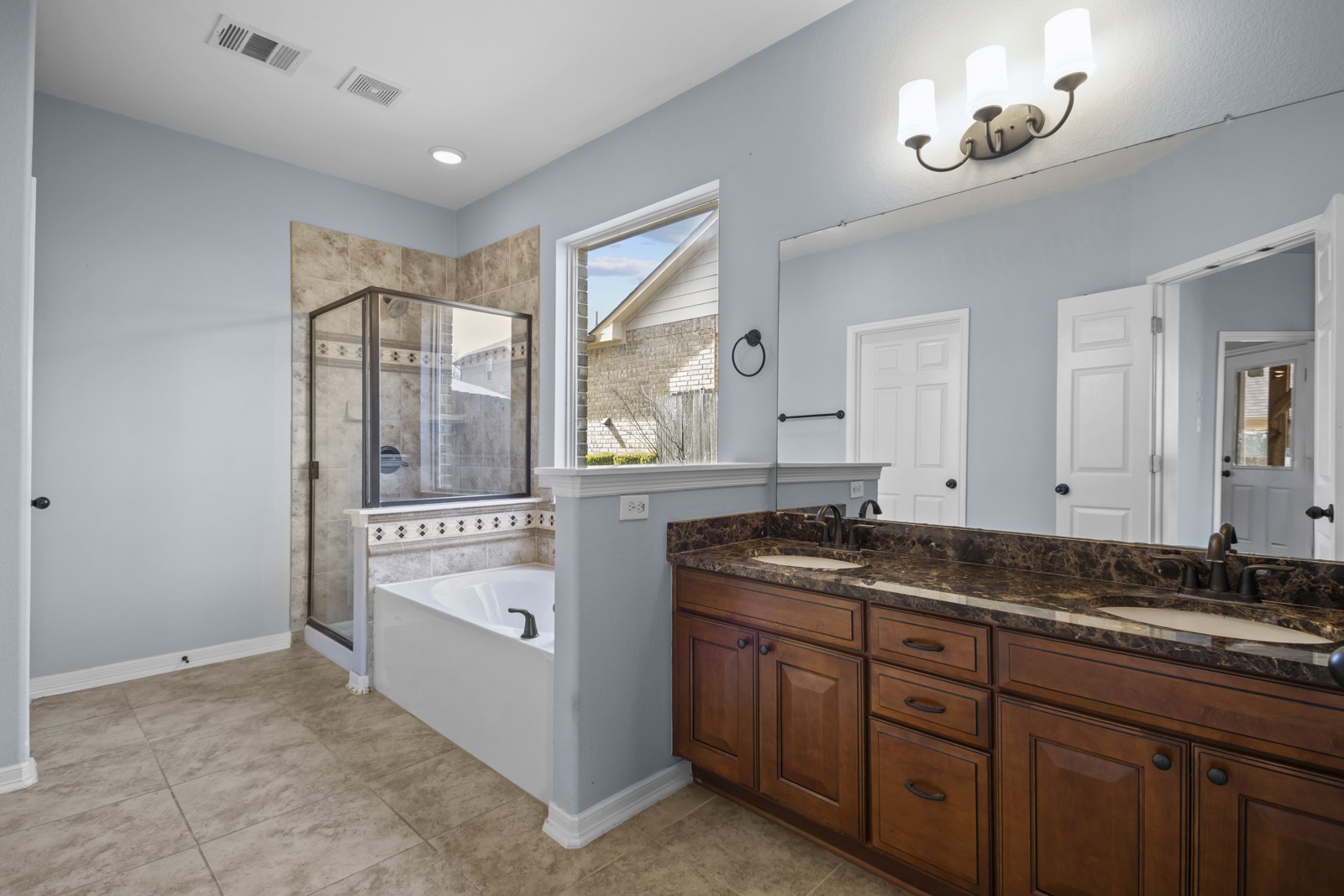 245 Razzmatazz Trail Buda, TX 78610 - Photo 21 of 40 Bathroom featuring double vanity, a shower stall, a garden tub, and light tile patterned floors
