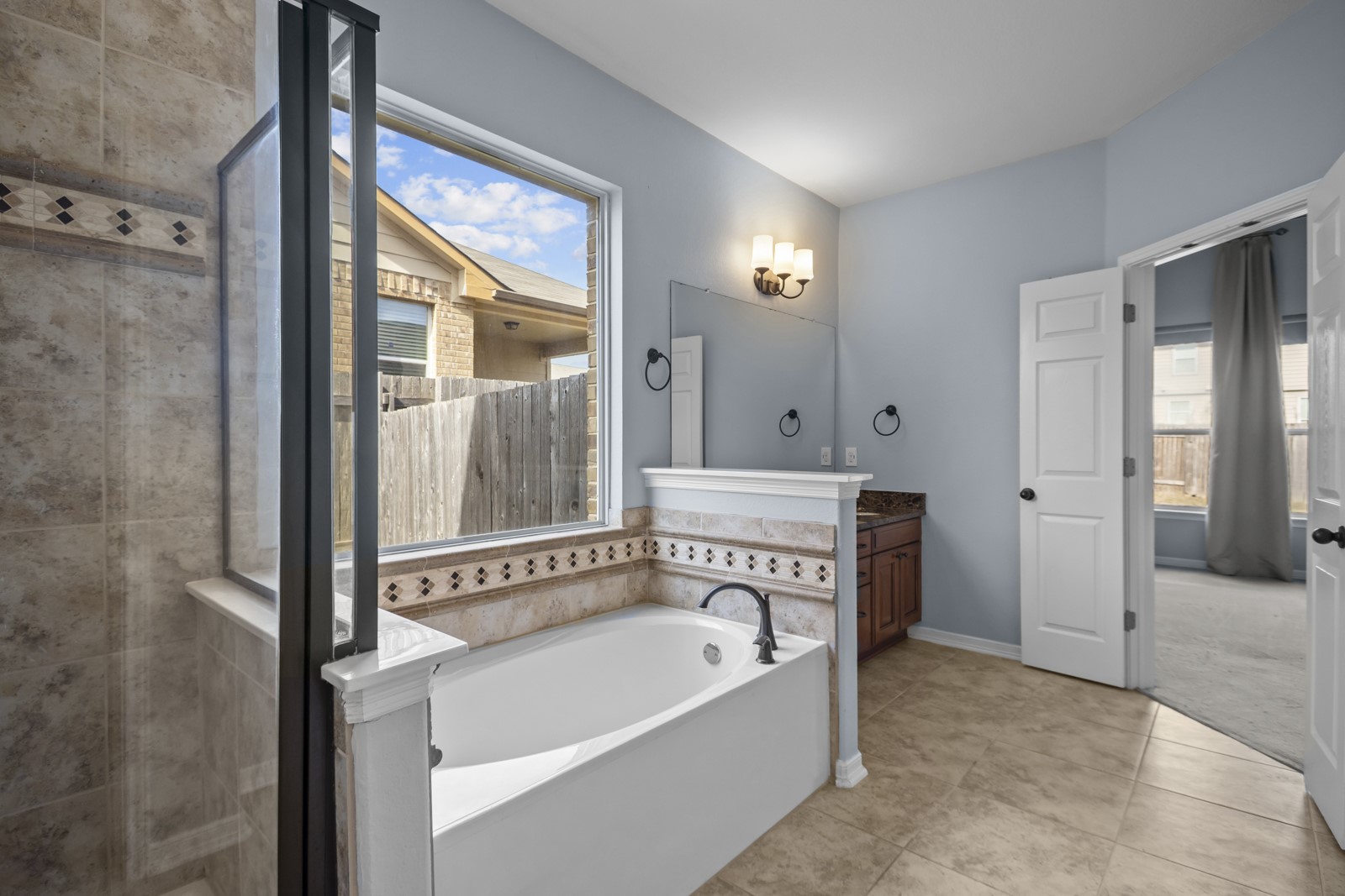 245 Razzmatazz Trail Buda, TX 78610 - Photo 22 of 40 Full bath with vanity, a shower stall, a garden tub, and light tile patterned floors