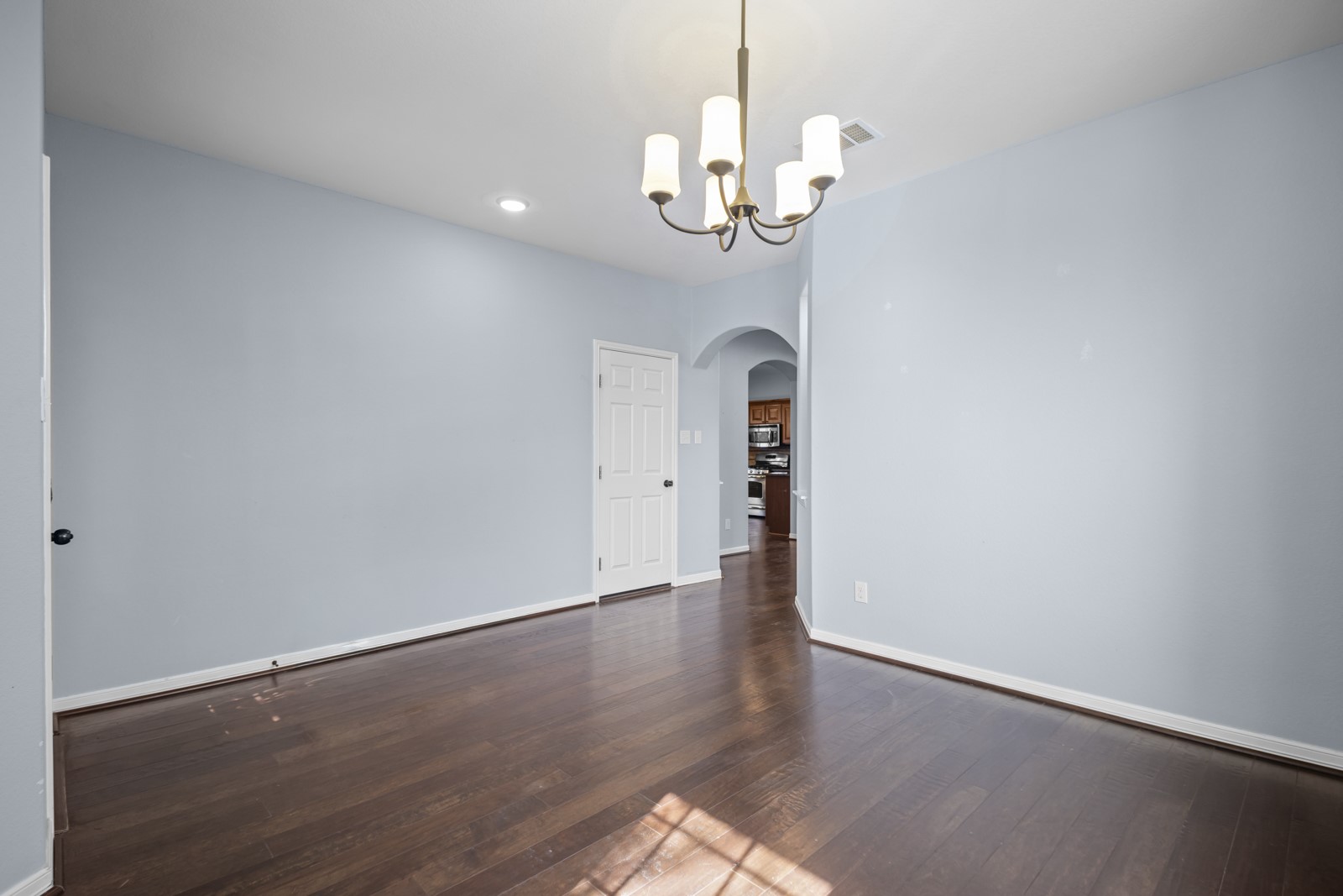245 Razzmatazz Trail Buda, TX 78610 - Photo 6 of 40 Empty room with arched walkways, hanging lights, and dark wood finished floors