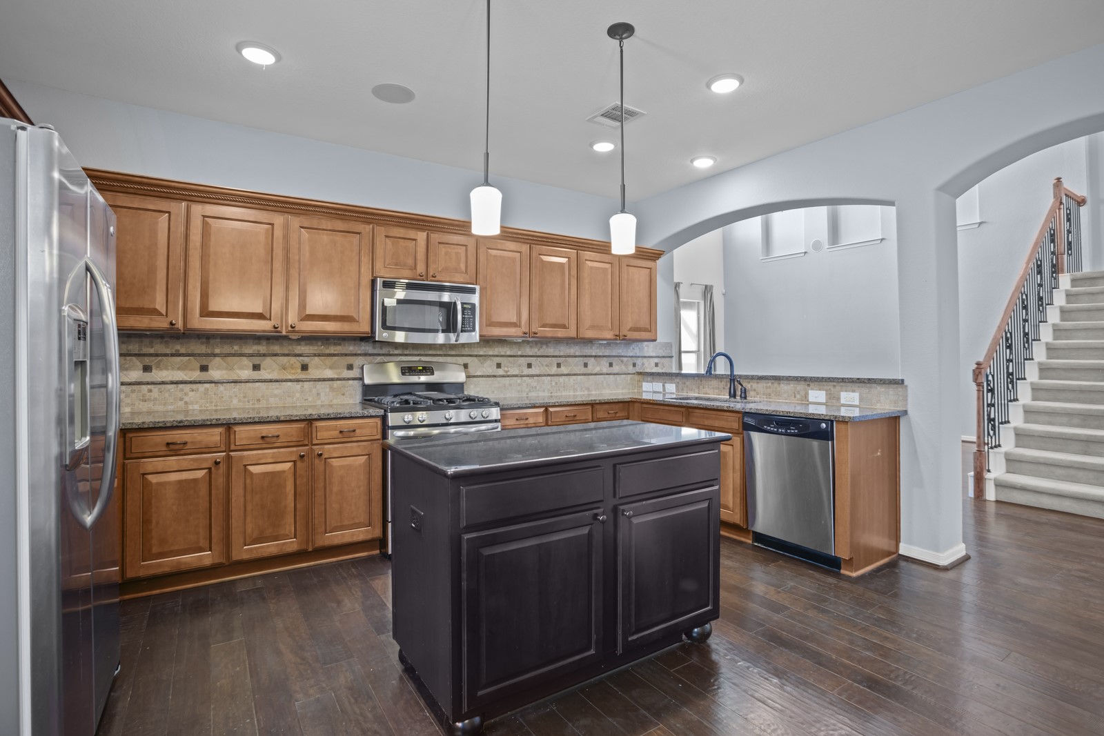245 Razzmatazz Trail Buda, TX 78610 - Photo 10 of 40 Kitchen with stainless steel appliances, backsplash, hanging light fixtures, a center island, and two tone color scheme