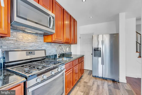 a kitchen with stainless steel appliances granite countertop a stove a refrigerator and a stove top oven