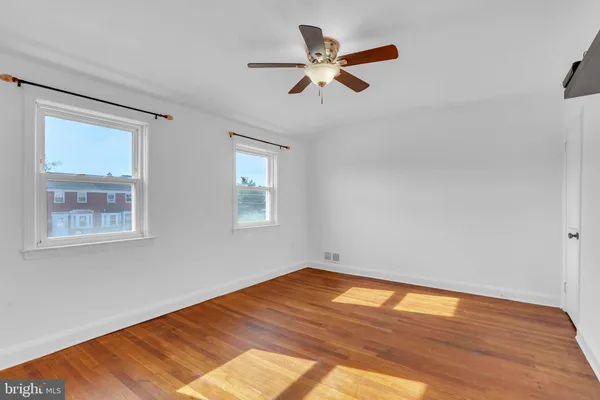 a view of empty room with wooden floor and fan