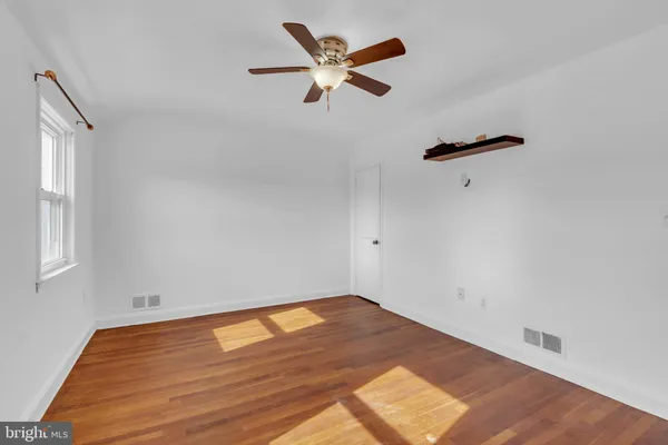 an empty room with wooden floor fan and windows
