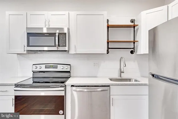a kitchen with stainless steel appliances a stove microwave and sink