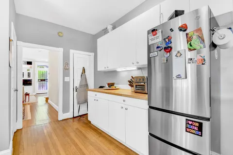 a large kitchen with a refrigerator a sink and white cabinets