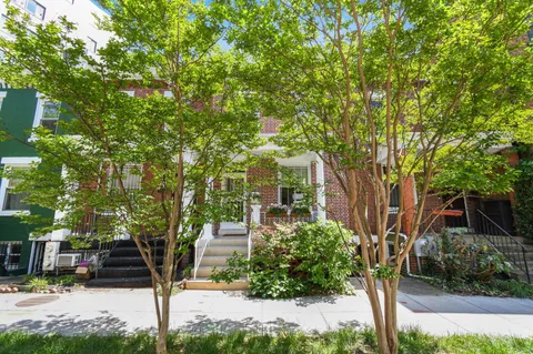 a front view of a house with a tree