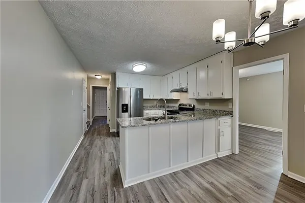 a kitchen with kitchen island granite countertop a sink cabinets and wooden floor