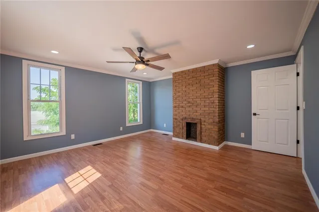 a view of an empty room with wooden floor fireplace and a window