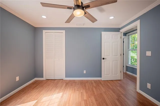 an empty room with wooden floor closet and windows