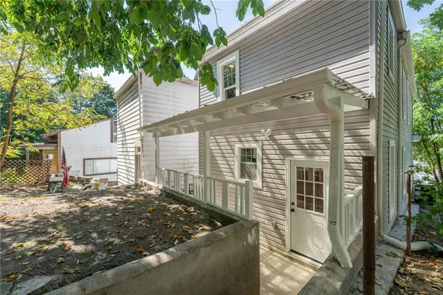 a view of a house with a small yard and large tree