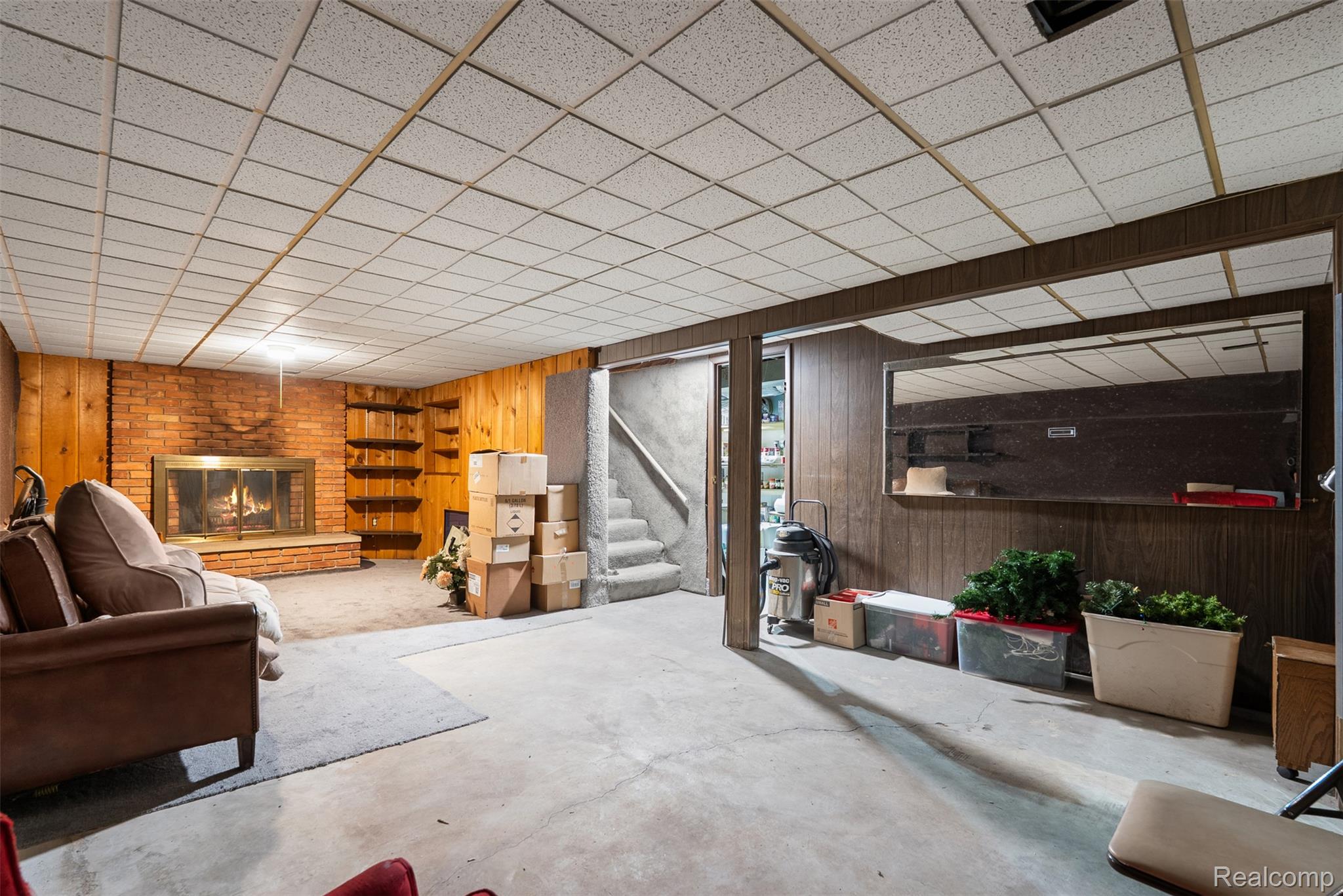 7192 Torrey Road Swartz Creek, MI 48473 - Photo 16 of 27 Living room featuring wooden walls, a brick fireplace, concrete floors, and a paneled ceiling
