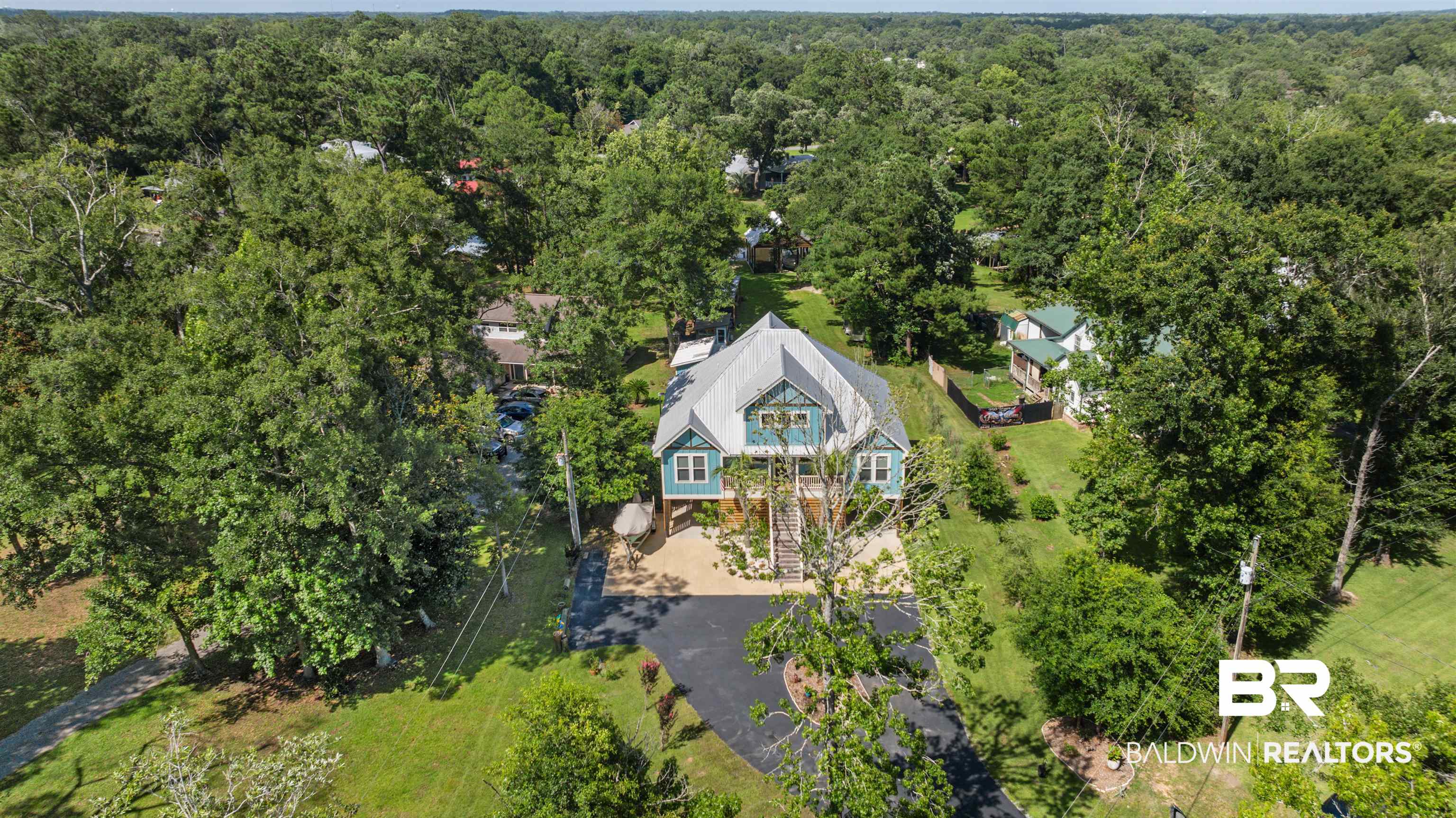 7266 Franklin Road Foley, AL 36535 - Photo 61 of 64 Elevated light blue exterior with white trim, featuring a prominent metal roof and a spacious paved driveway