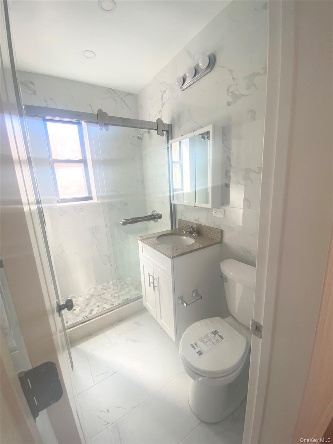 37-21 80th Street, Unit 4M Queens, NY 11372 - Photo 15 of 16 a bathroom with a granite countertop toilet a sink and a mirror