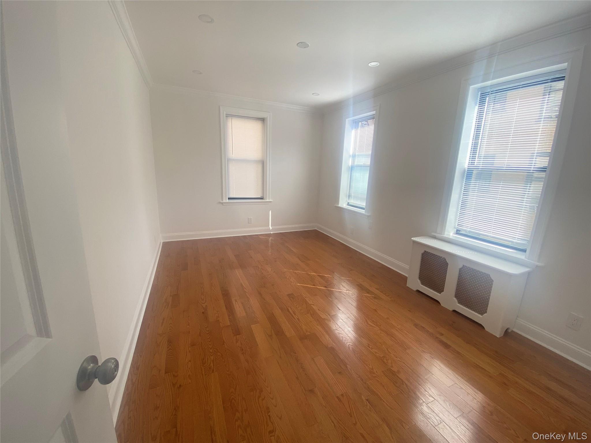 37-21 80th Street, Unit 4M Queens, NY 11372 - Photo 16 of 16 an empty room with wooden floor and windows