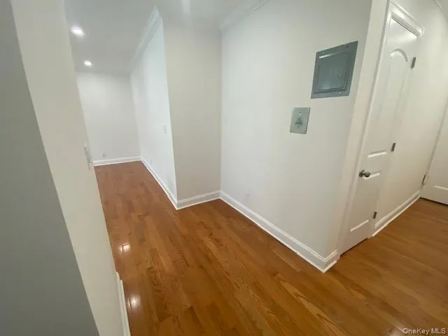 a view of a hallway with wooden floor and a bathroom